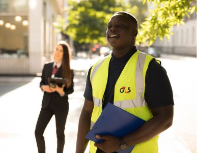 Smiling G4S worker in vest holding clipboard outdoors