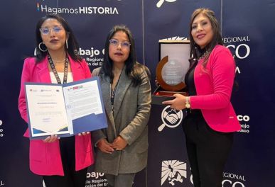 Three women holding award and certificate at event.