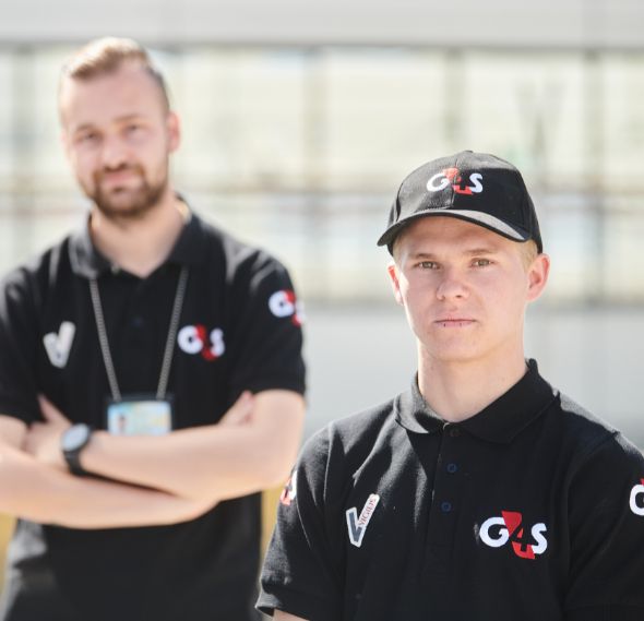 Two G4S security staff standing outside in uniform.