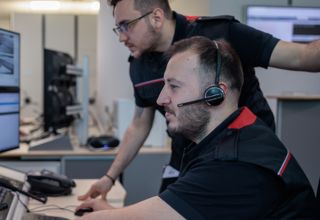 Two men working at desks with many computers screens.