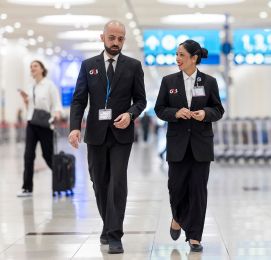 Two people in uniform walking inside a bright building.