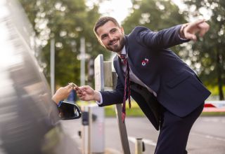 Smiling G4S employee pointing while handing ID to person.