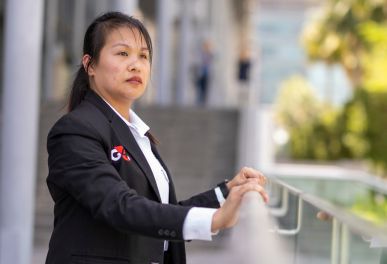Woman in formal wear standing near glass railing outside.