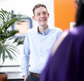 Man in blue shirt smiling during office chat.
