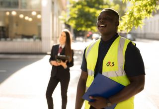 Smiling G4S worker in vest holding clipboard outdoors