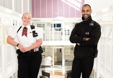 Two prison custody officers standing inside a secure facility.