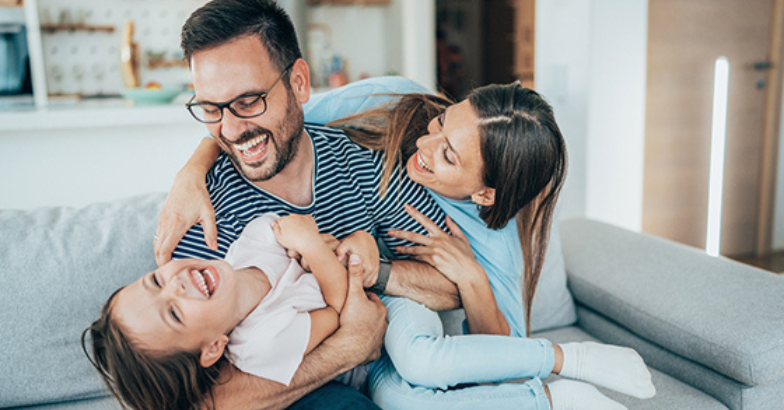 Family laughing together on sofa