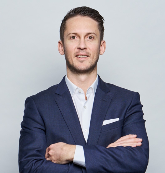 Smiling man in navy suit with arms crossed