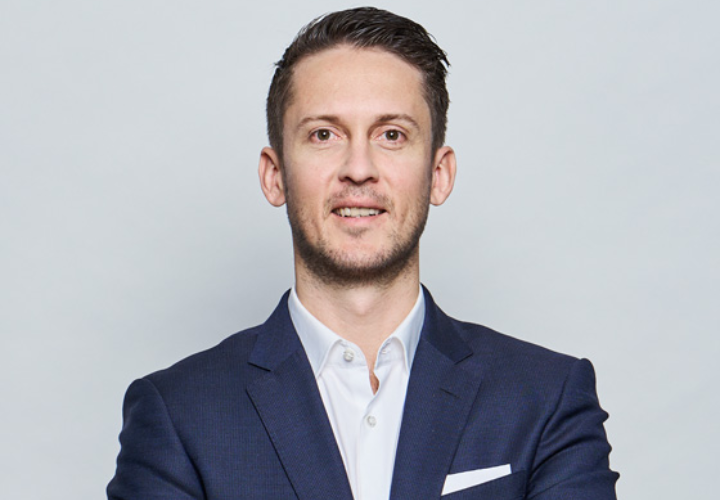 Lächelnder Mann mit verschränkten Armen im Anzug