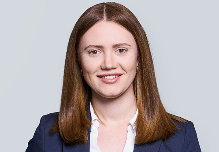 Frau im Business-Outfit lächelt vor hellem Hintergrund