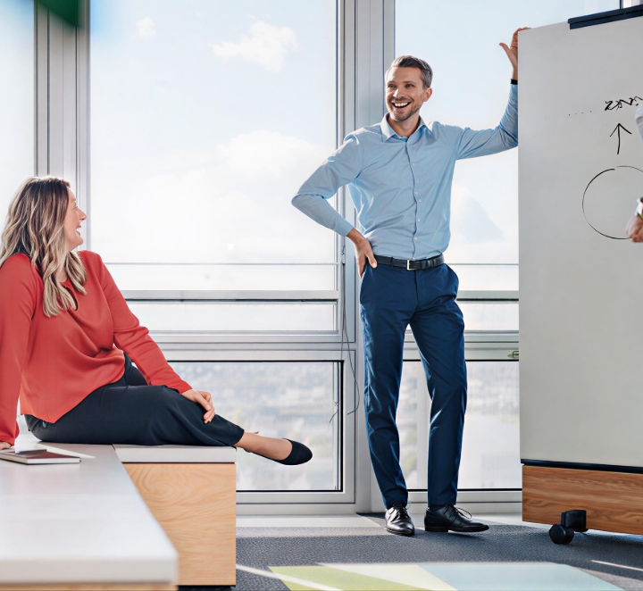 Coworkers chatting by whiteboard in bright office