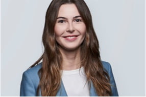 A smiling young professional in a light blue blazer