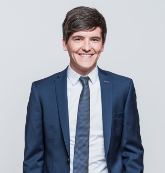 Smiling man in blue suit posing against light backdrop