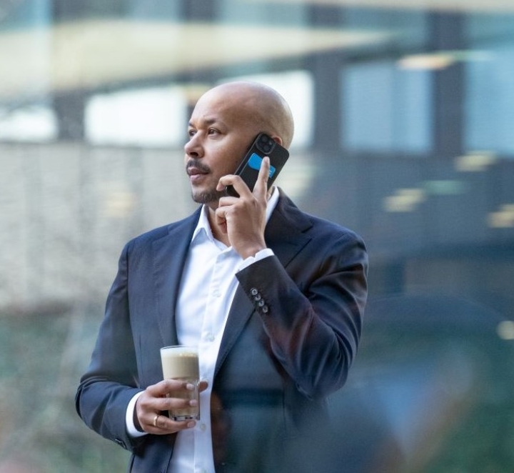 Man in suit talks on phone with coffee cup.