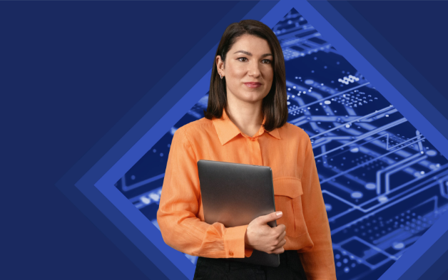 Woman in an orange blouse holding a laptop, standing in front of a technical background.