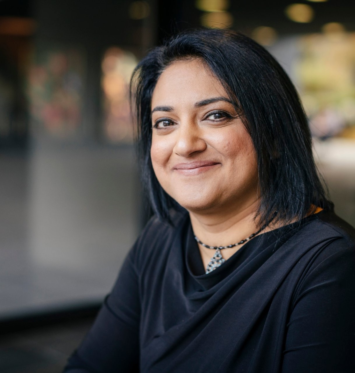 Smiling woman in front of a blurry background.