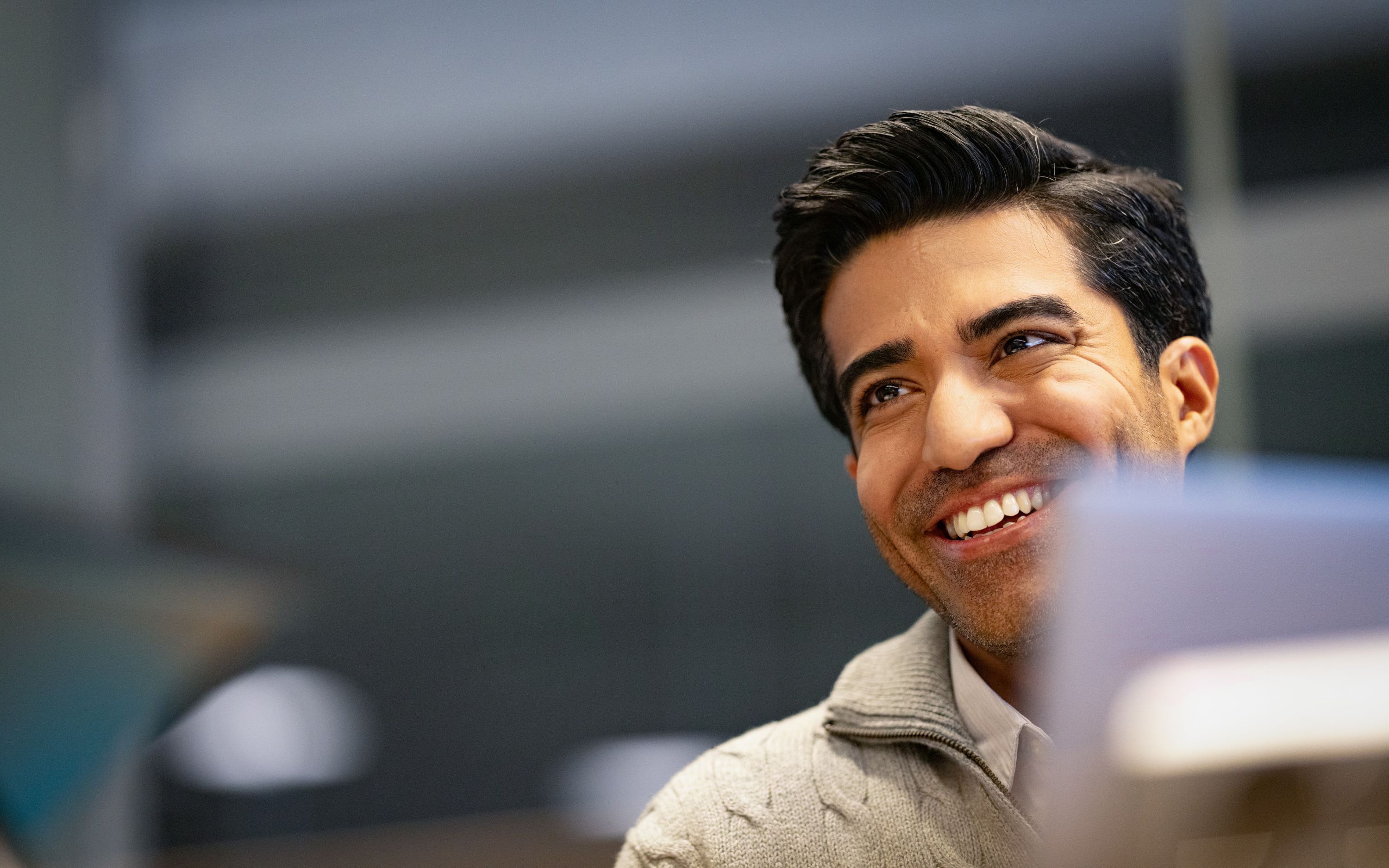 Young man smiling to another person that is not in the image.