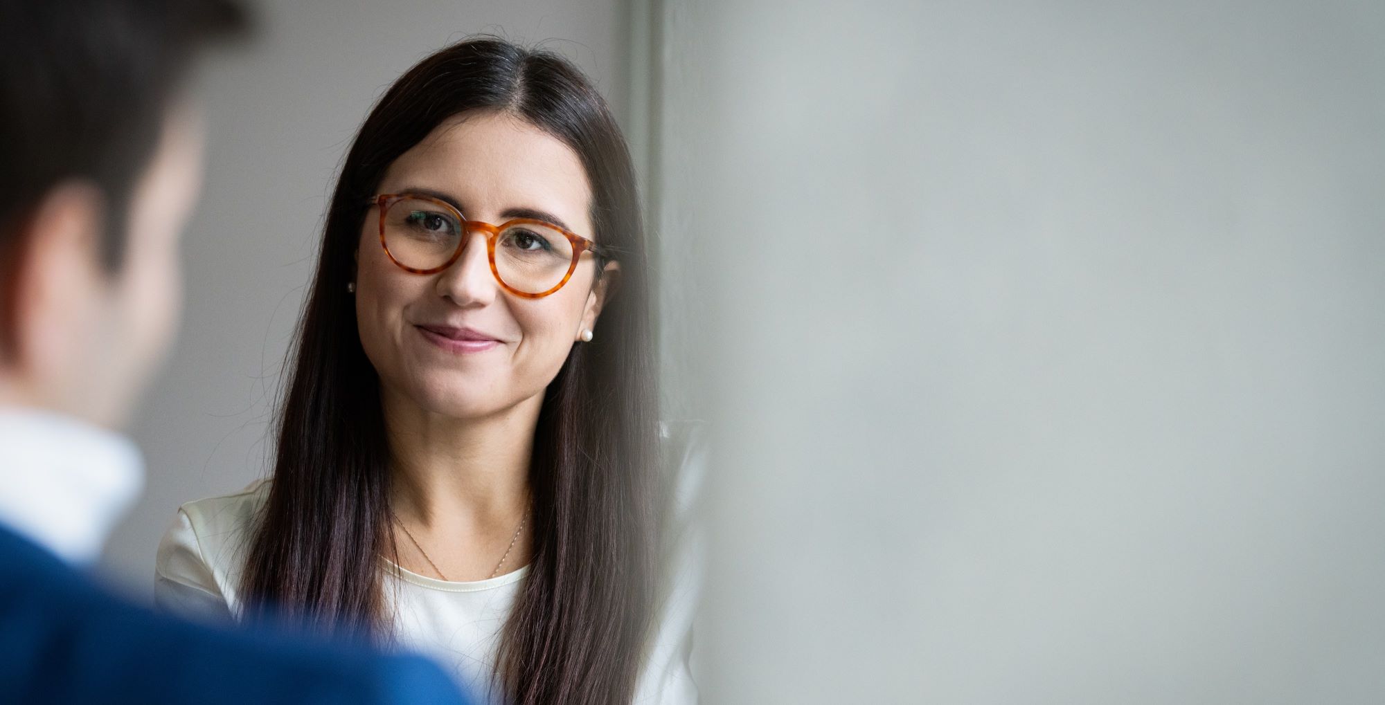 Young women with glasses talking to a colleague.