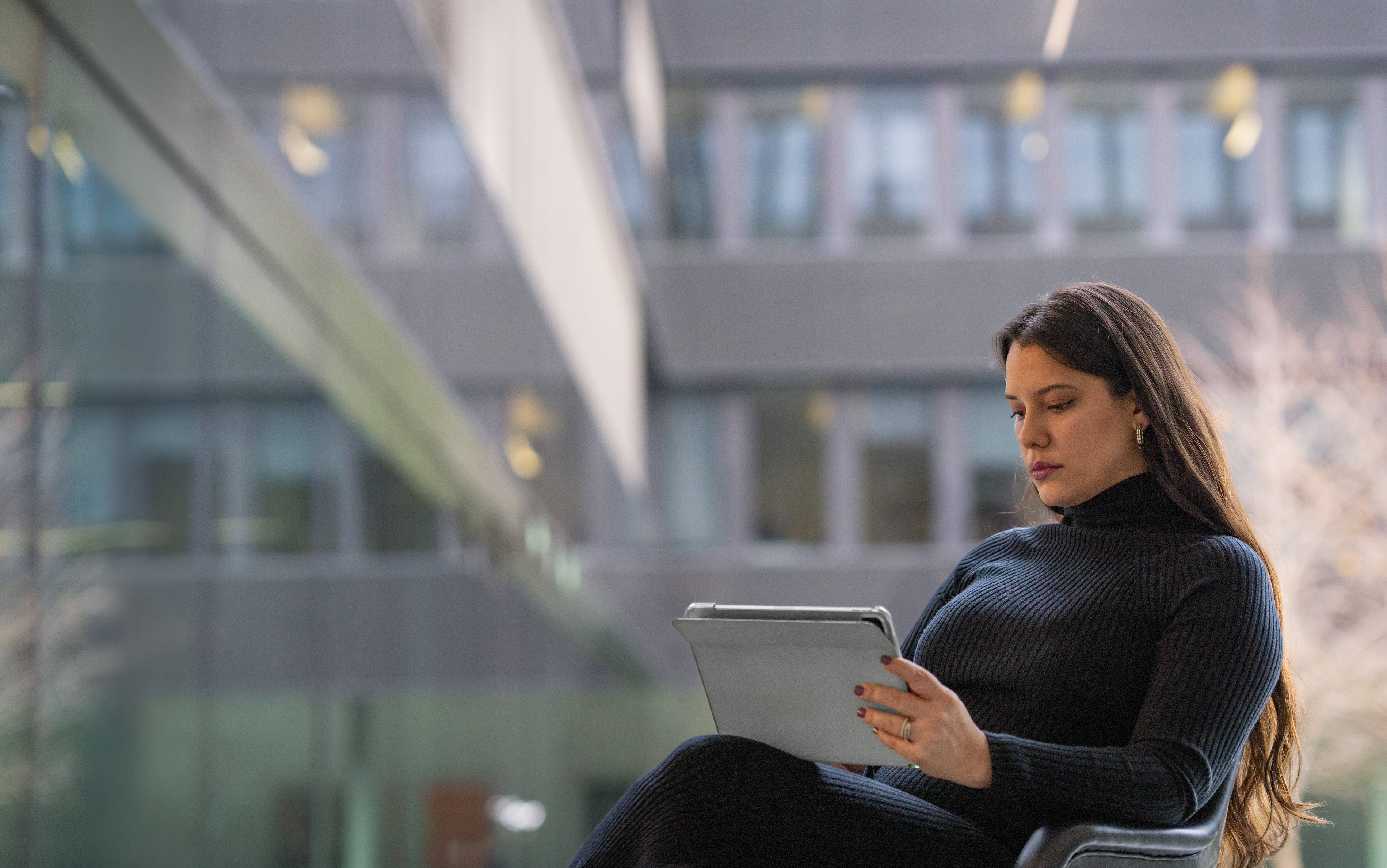 Young woman working on a laptop in a modern office environment.