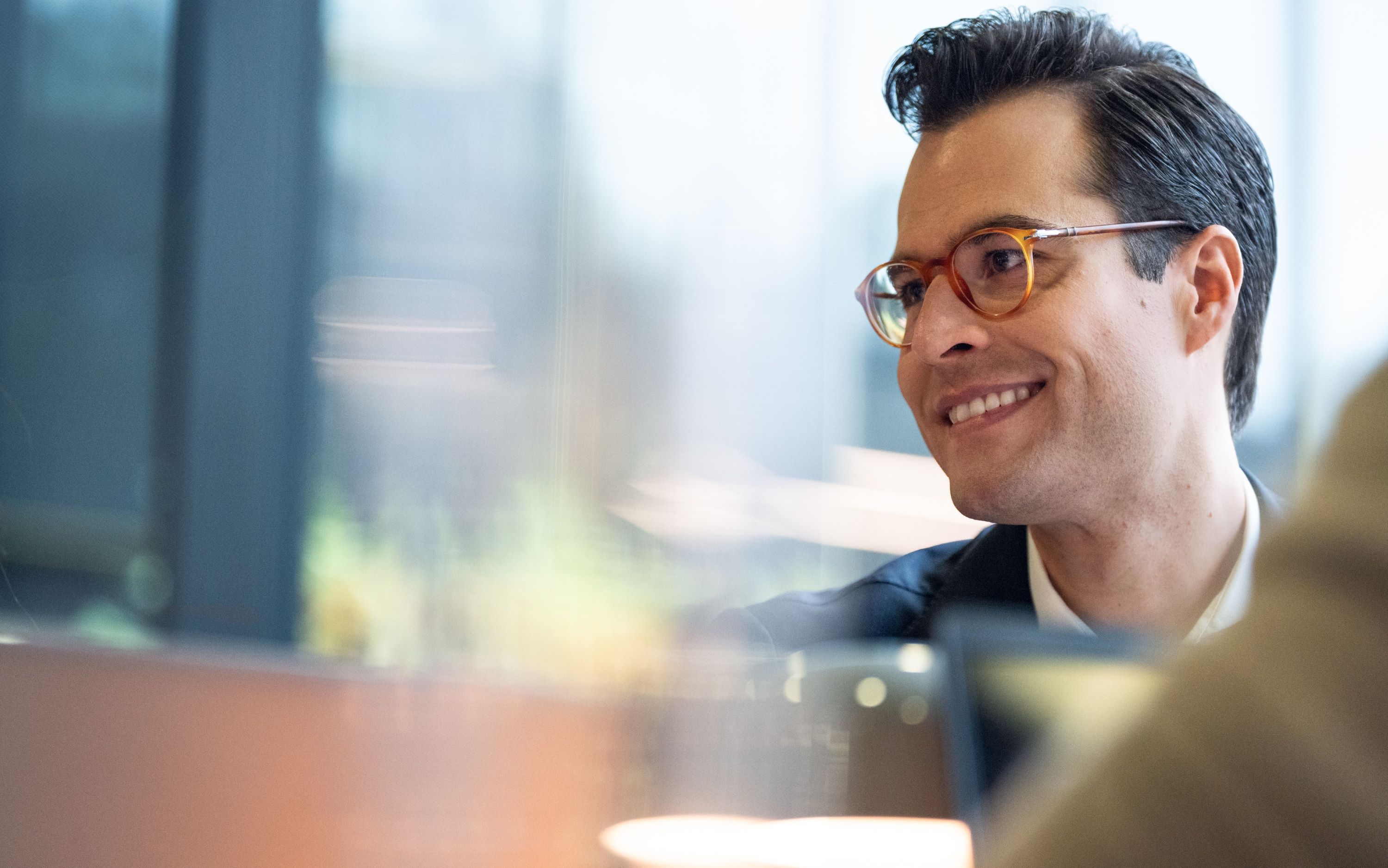 Young man with glasses laughing, not looking into the camera.