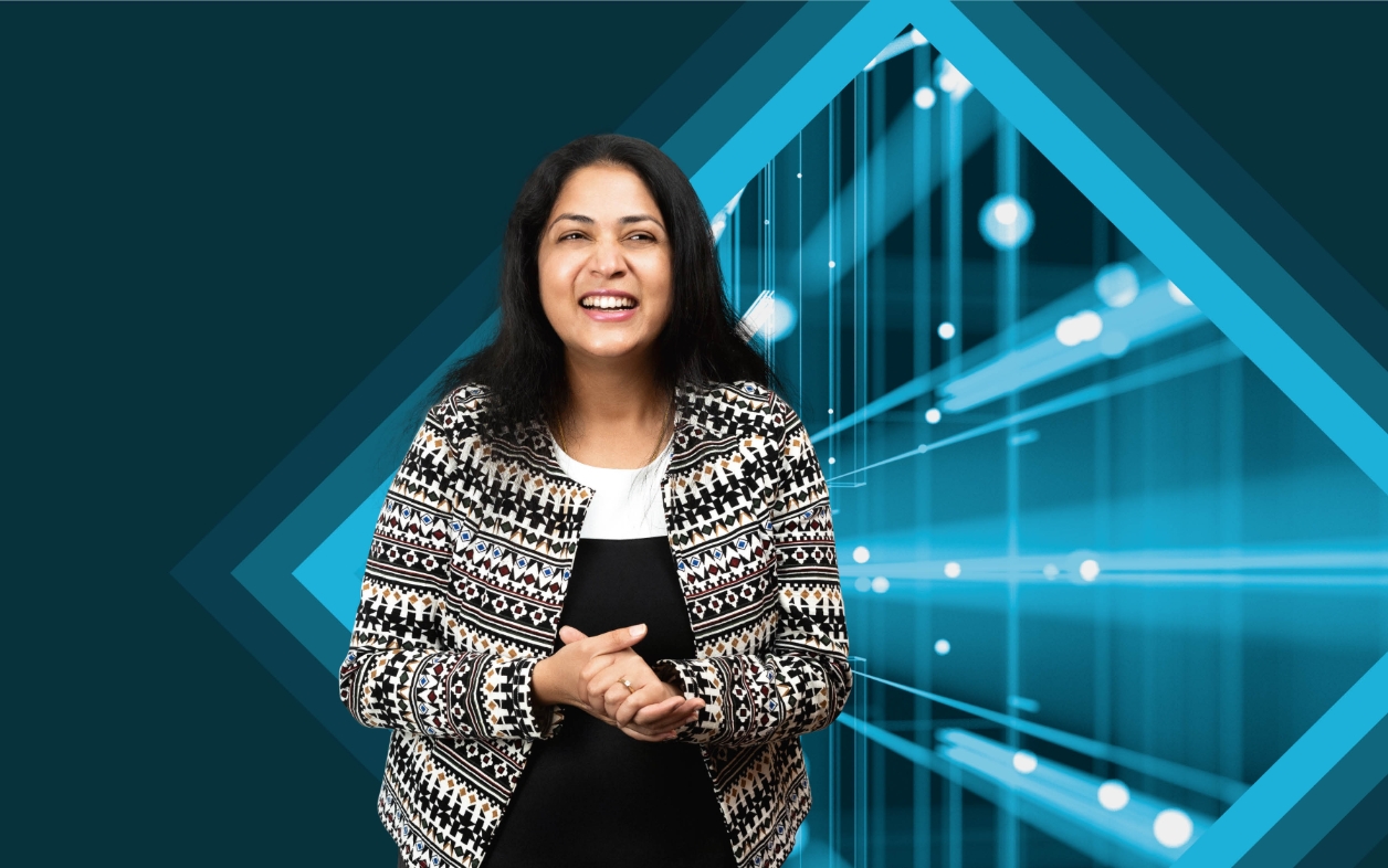Woman standing and smiling with blue lights behind.