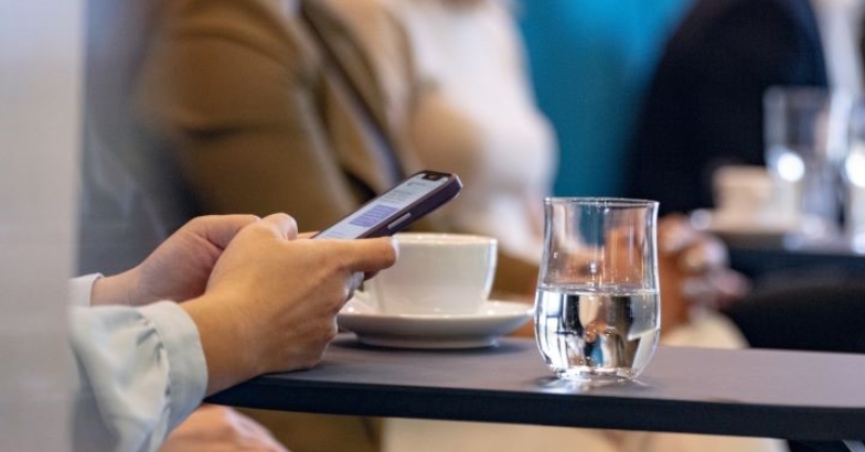 Person holding a phone at a business meeting with drinks