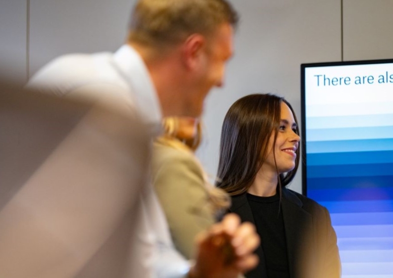 People engaged in a discussion near a screen with gradient bars