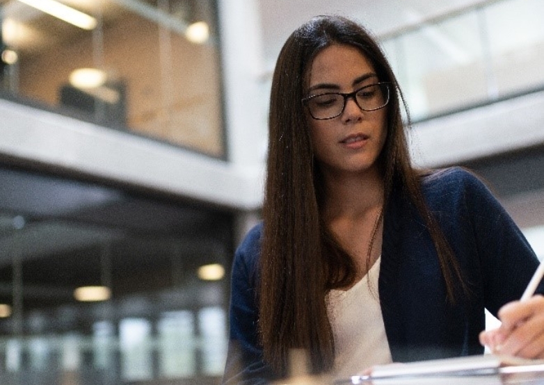 Frau mit Brille schreibt im modernen Bürogebäude