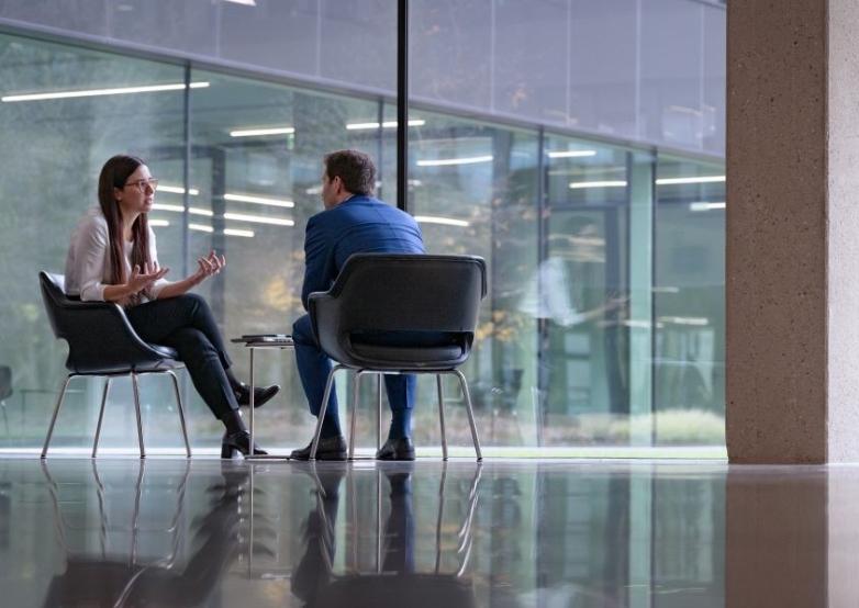 Two colleagues having a discussion in a modern glass office