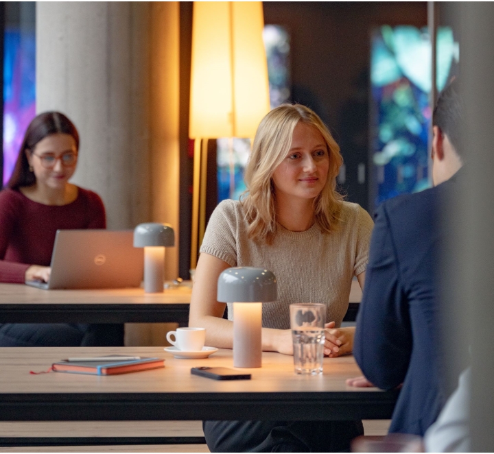 People talking at a cafe table with lamps.