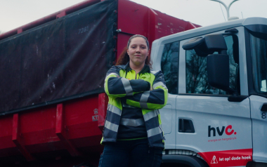 Medewerker staat bij vrachtwagen met zelfvertrouwen.