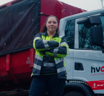 Medewerker staat bij vrachtwagen met zelfvertrouwen.