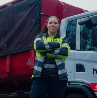 Medewerker staat bij vrachtwagen met zelfvertrouwen.