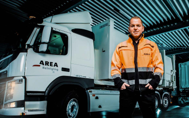 Medewerker in oranje jas bij vrachtwagen