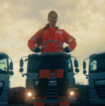 Medewerker in rode werkkleding bij vrachtwagens