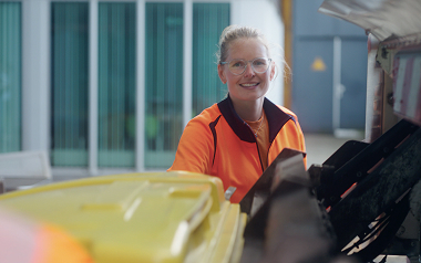 Medewerker in oranje werkkleding op werkplek