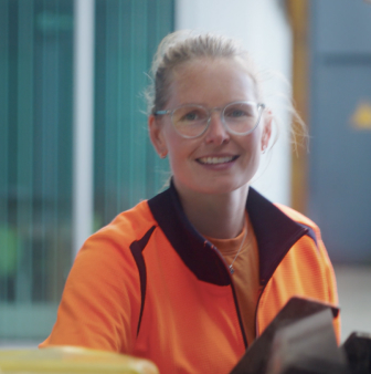 Medewerker in oranje werkkleding op werkplek