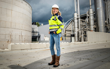 Vrouw in helm bij fabriek onder donkere lucht nu!