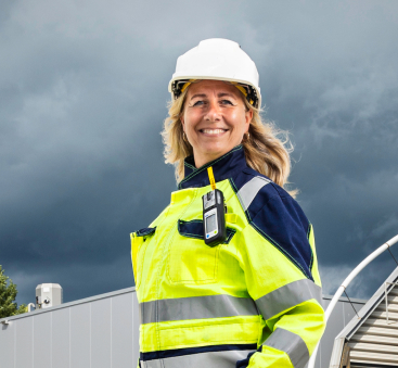 Vrouw in helm bij fabriek onder donkere lucht nu!