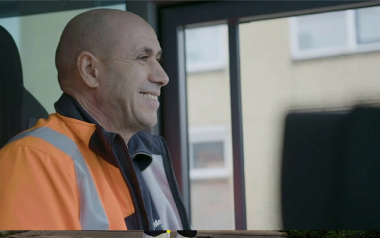 Vuilnisman lacht in cabine van vrachtwagen extra