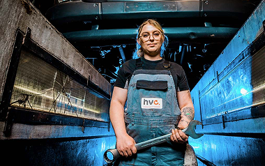 Monteur met bril houdt sleutel onder vrachtwagen in werkplaats