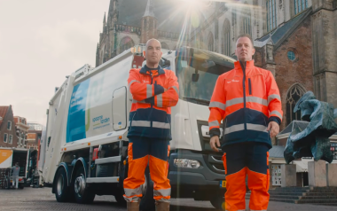 Dienstmannen bij vuilniswagen voor grote kerk stad