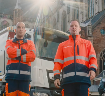 Dienstmannen bij vuilniswagen voor grote kerk stad