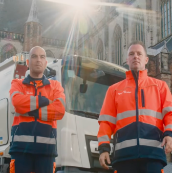 Dienstmannen bij vuilniswagen voor grote kerk stad