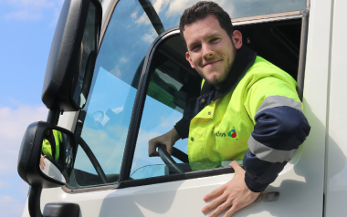 Chauffeur glimlacht vanuit cabine van witte vrachtwagen vandaag