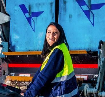 Vrouw met afvalbak naast vuilniswagen op straat!