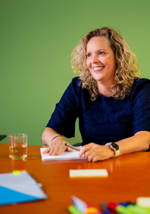 Vrouw lacht tijdens overleg aan tafel