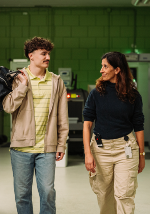 Begeleider loopt met jongere door gang