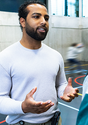 Begeleider praat rustig met man in sportzaal hier!