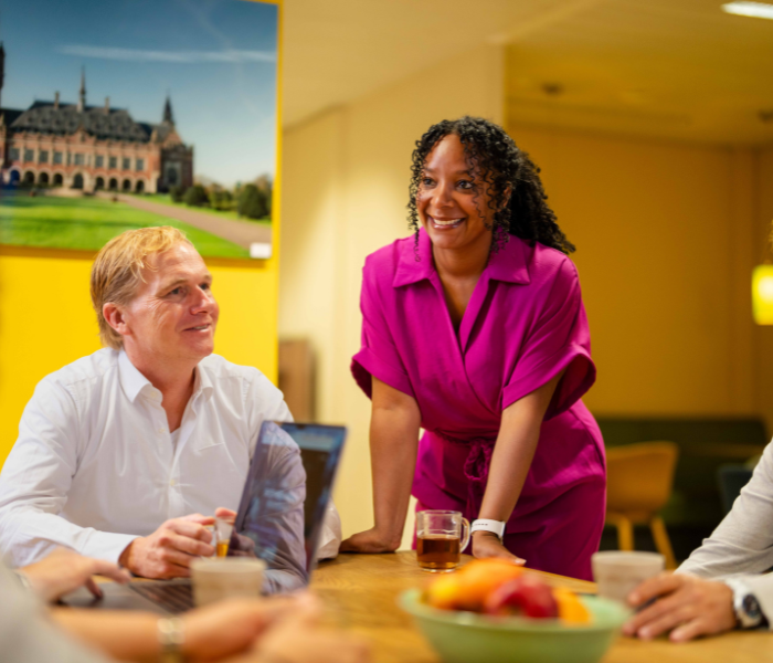 Overleg aan tafel met laptop en drankjes.